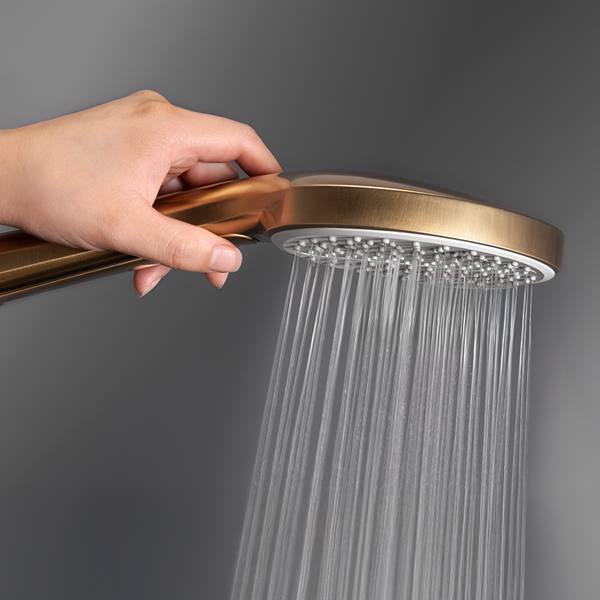Regadera dual dorada multichorro sostenida por una persona accionando el botón para el cambio de chorro